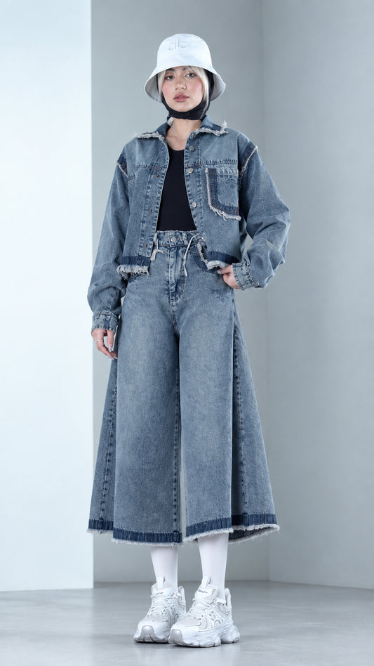 Front view of model wearing Denim Blue cropped raw hem denim jacket and matching wide leg culottes set