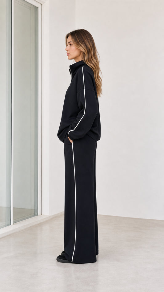 Side profile view of model wearing black 2-piece wide leg tracksuit set
