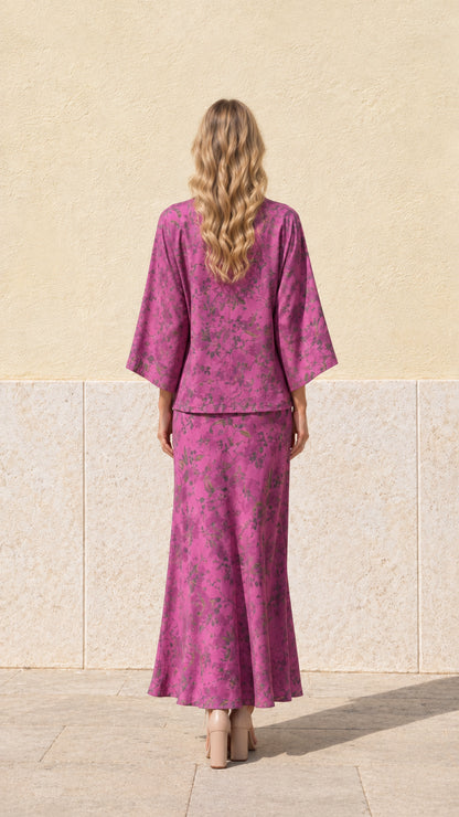 Back view of model wearing magenta floral print tie-front top and matching maxi skirt
