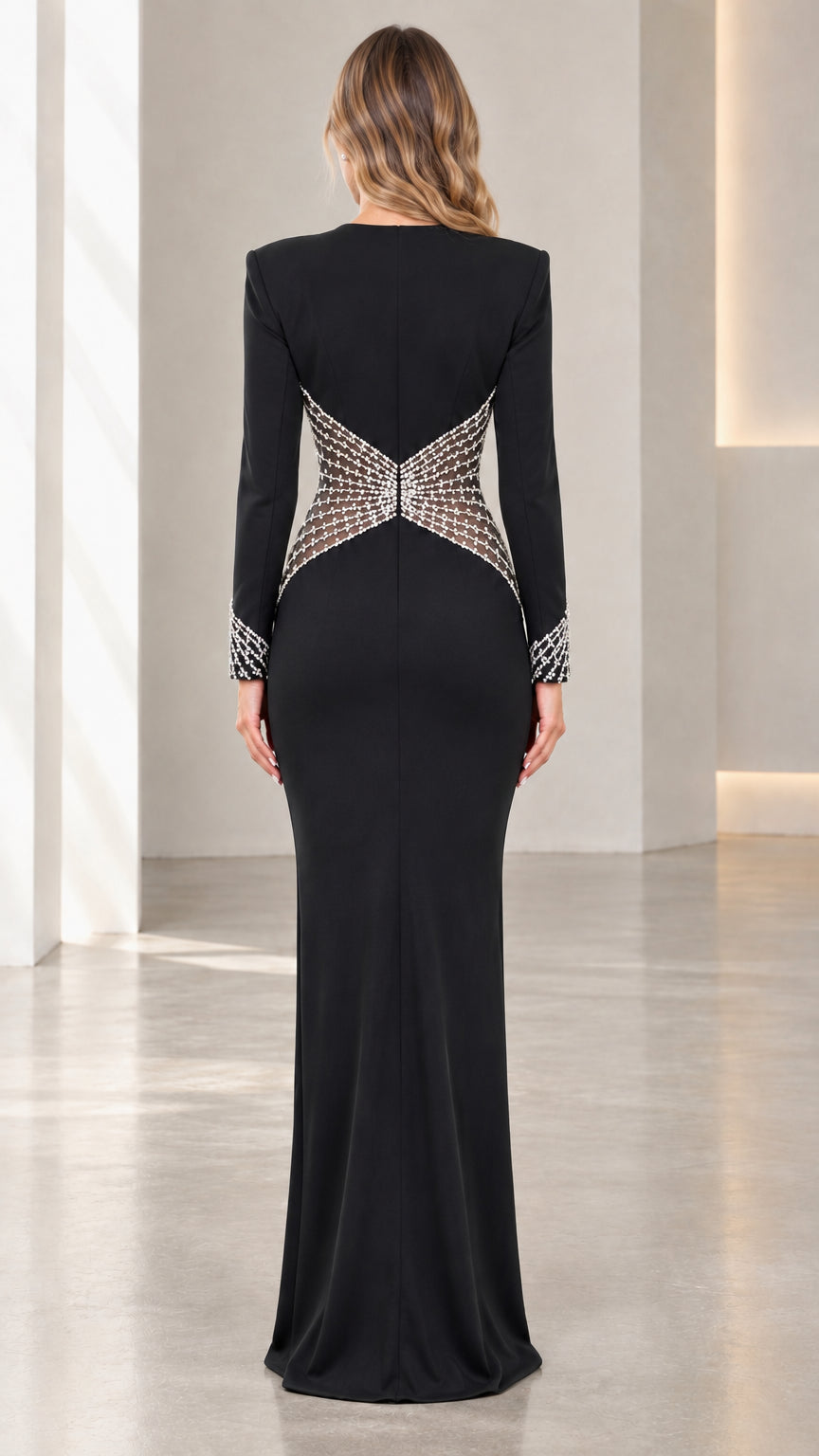 Back view of model wearing black floor-length gown featuring crystal-embellished mesh waist