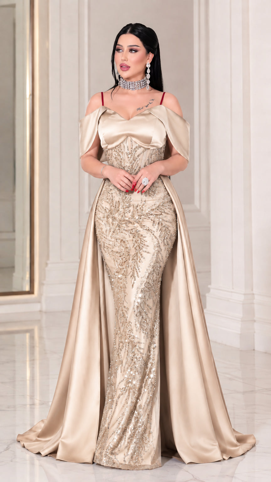Full-length front view of model wearing Champagne gold beaded off-the-shoulder mermaid gown with overskirt